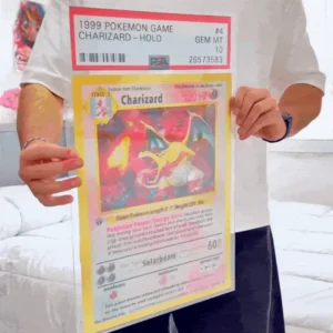 Person holding a large replica of a 1999 Charizard Pokémon card graded PSA 10, collectible toy from Xaudis